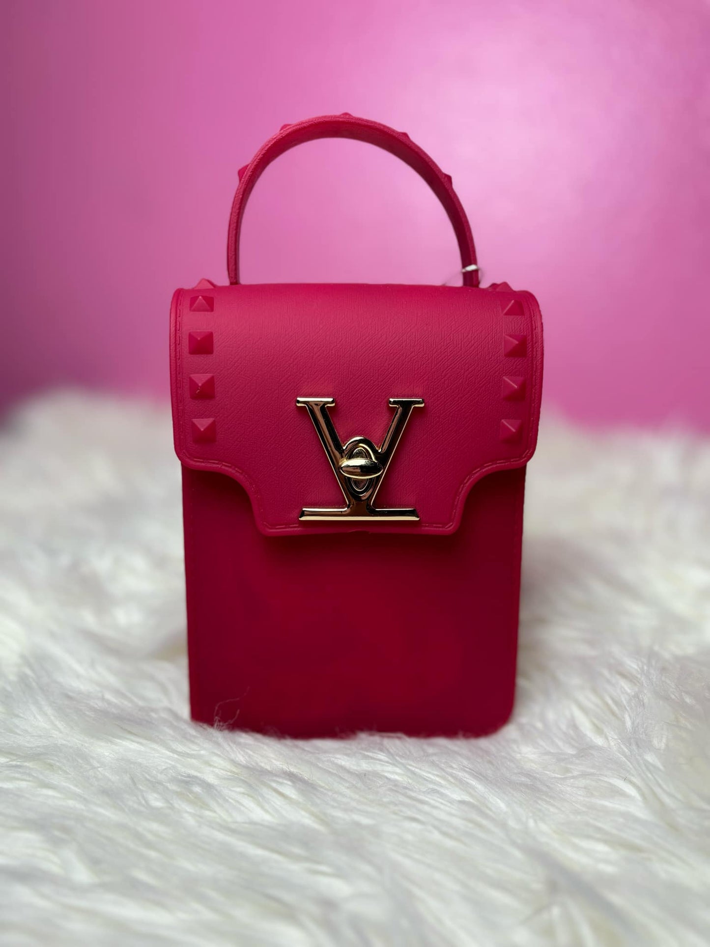 Burgandy handbag with a gold logo on a pink background